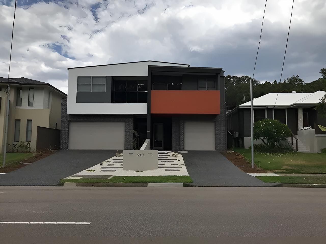 A House With Two Garages is Sitting on the Side of the Road — East Maitland Building In Tenambit, NSW