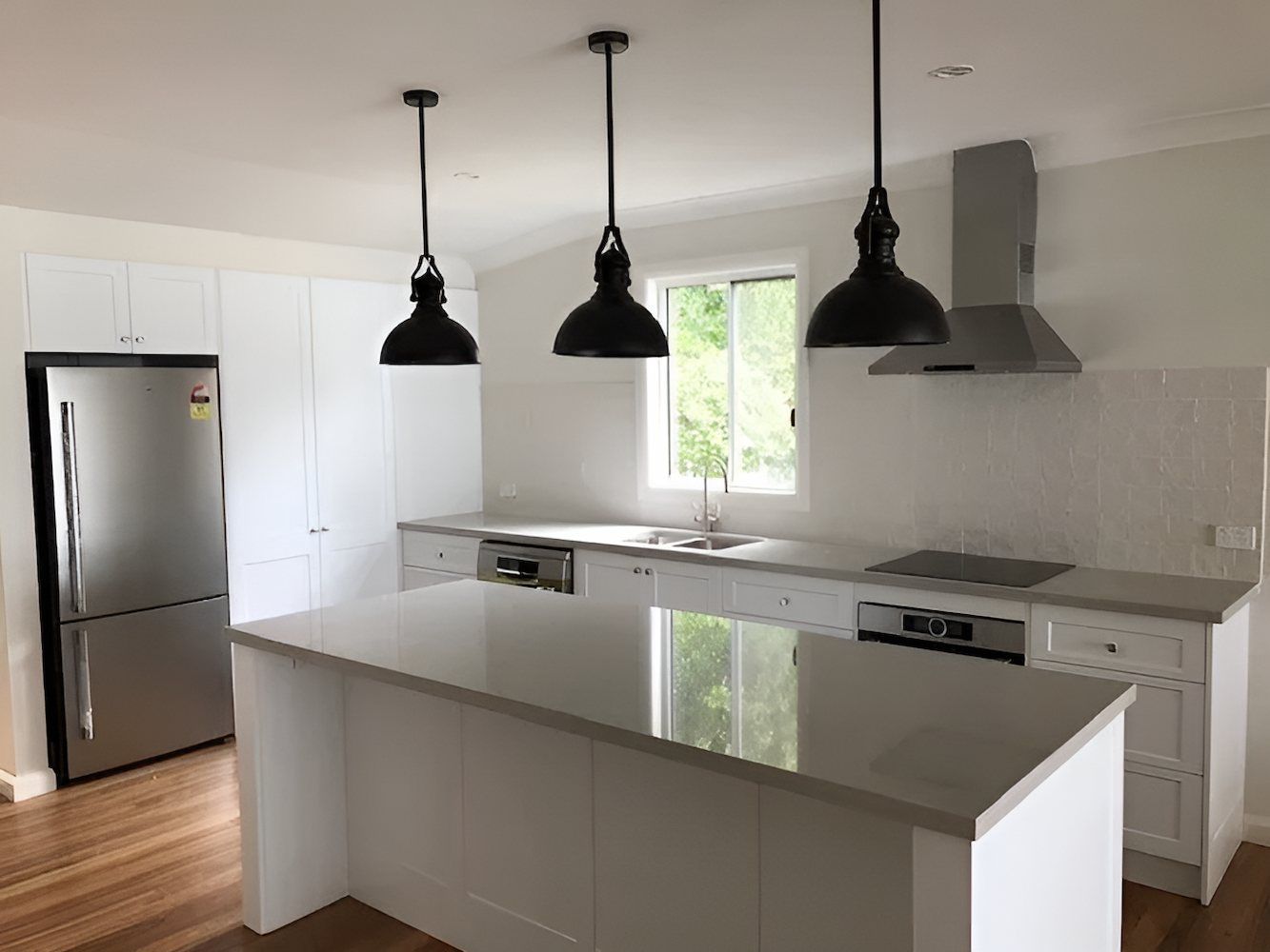 A Kitchen With White Cabinets, Stainless Steel Appliances and a Large Island — East Maitland Building In Tenambit, NSW