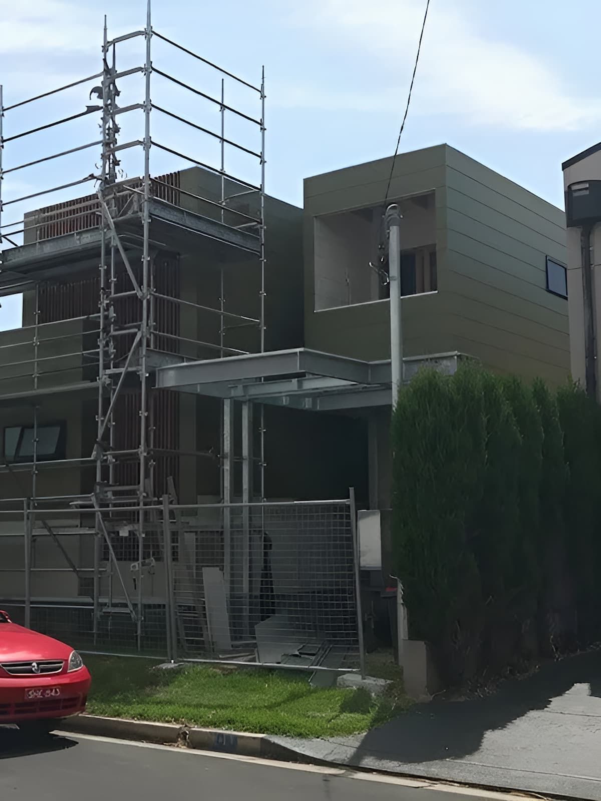 A Red Car is Parked in Front of a Building Under Construction — East Maitland Building In Newcastle, NSW