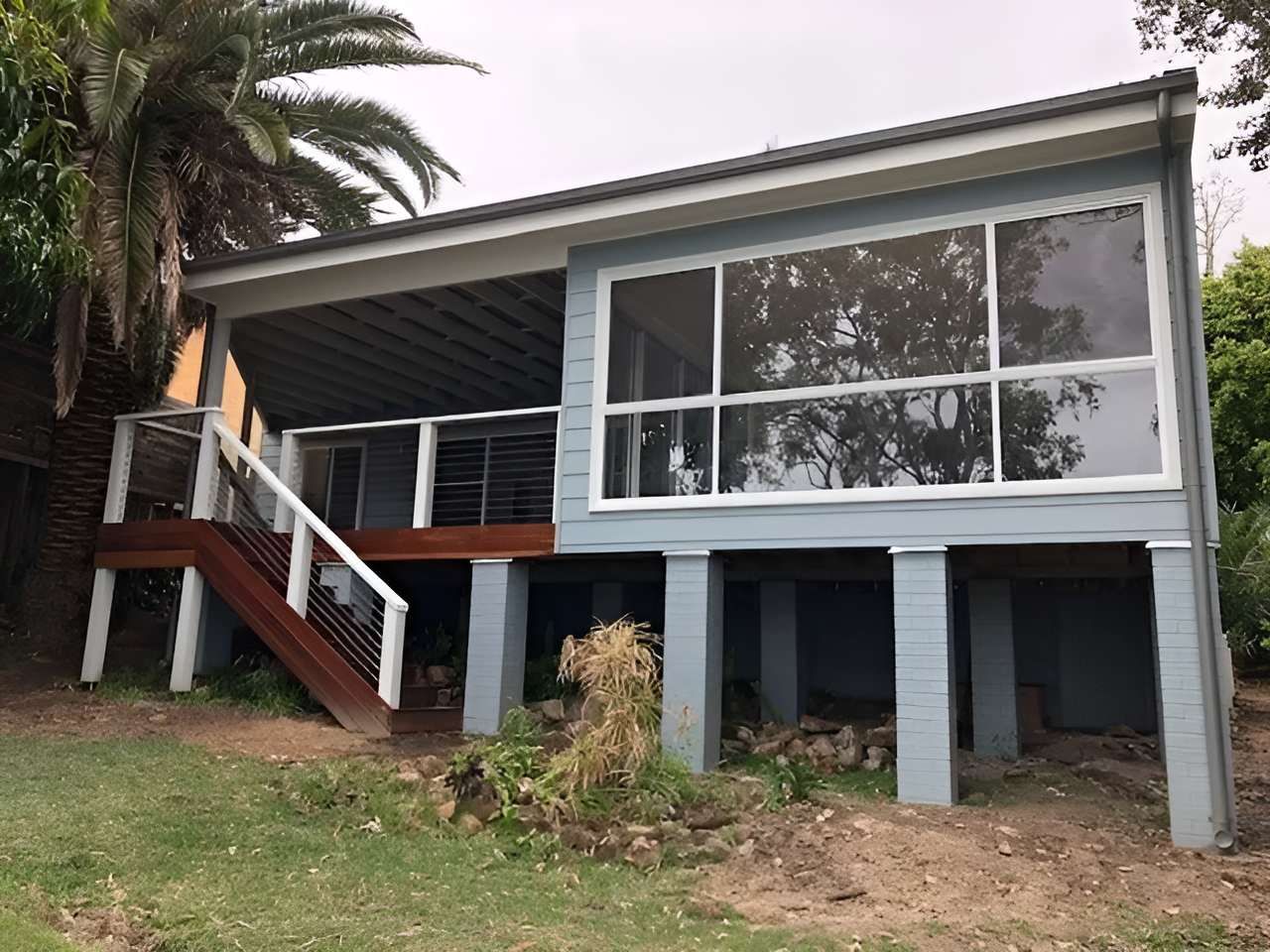 A Blue House With a Deck and Stairs is Sitting on Top of a Hill — East Maitland Building In Port Stephens, NSW