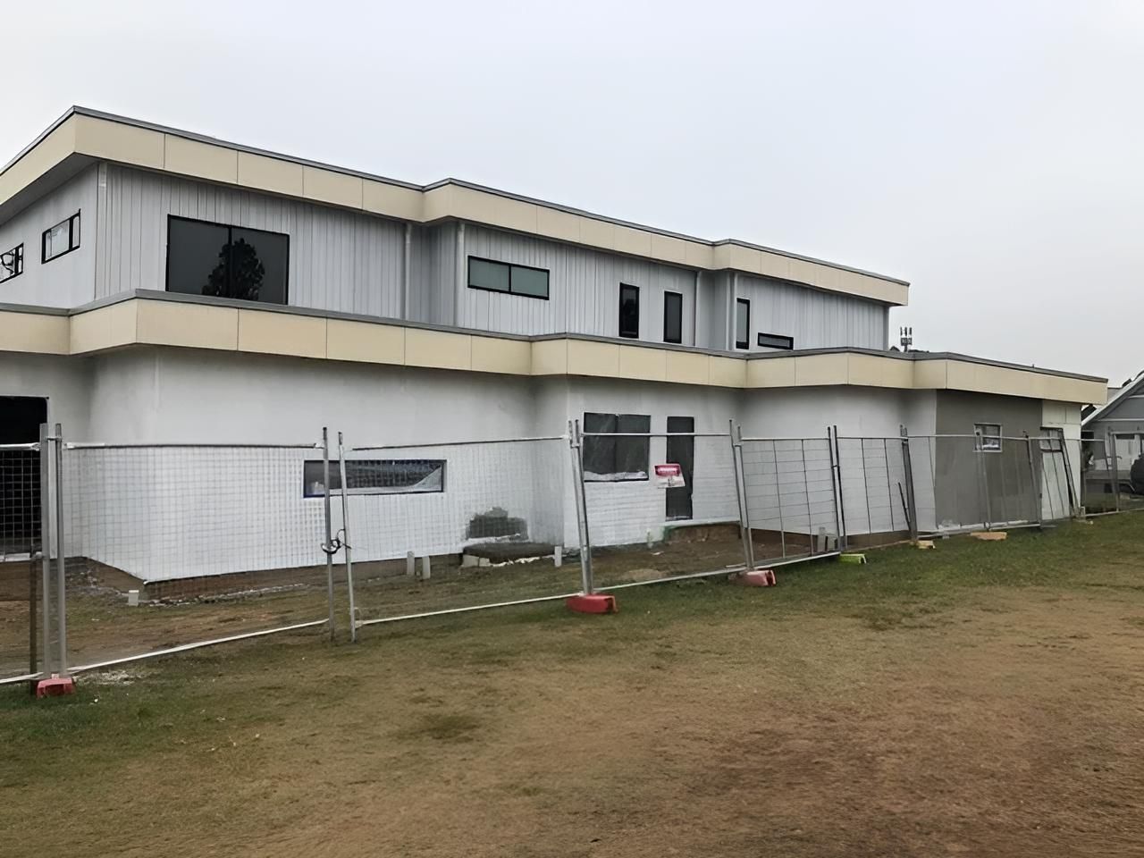 A Large White Building With a Fence Around It is Being Built — East Maitland Building In Maitland, NSW