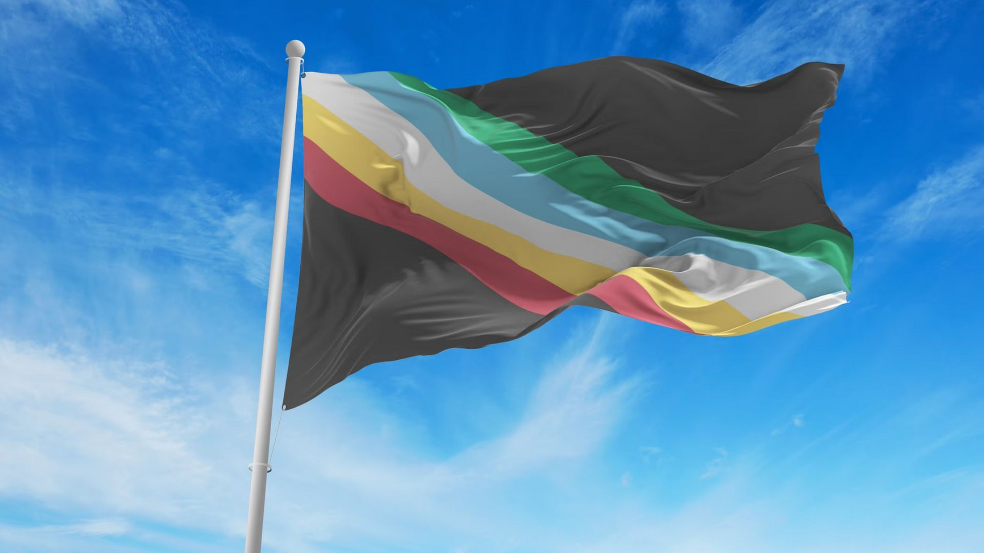 The Disability Pride Flag flies in front of a blue sky. 