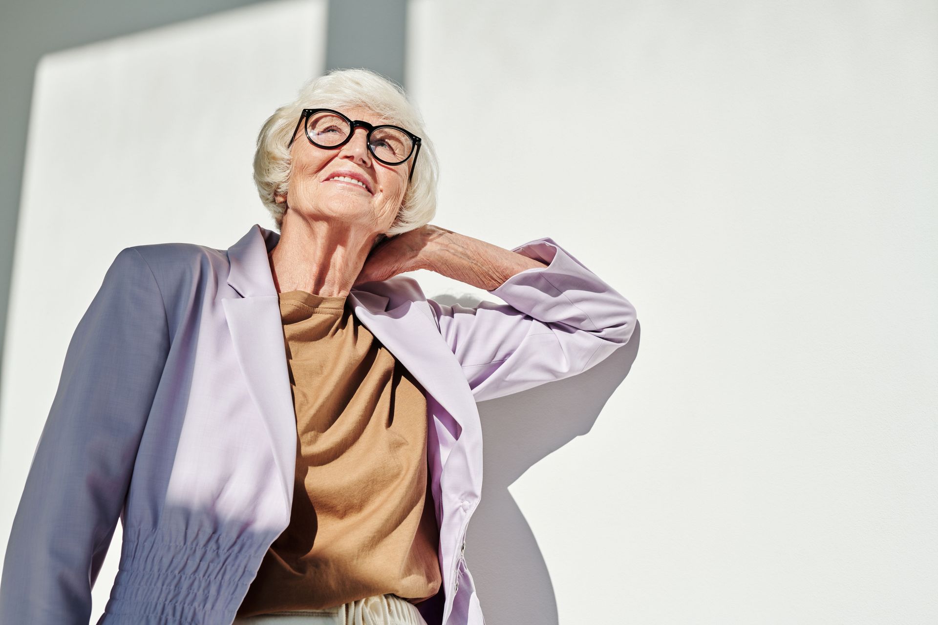An older woman leans back in sunlight, eyes closed.