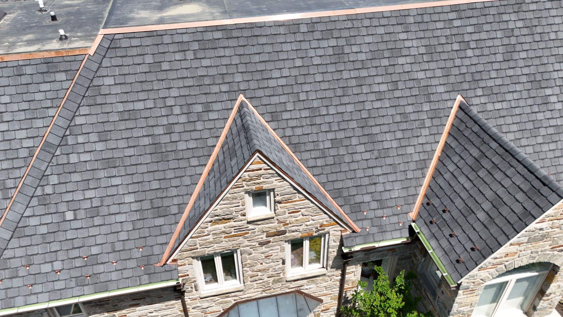Stone house rooftops with dark gray shingles and two steep gables, seen from above.