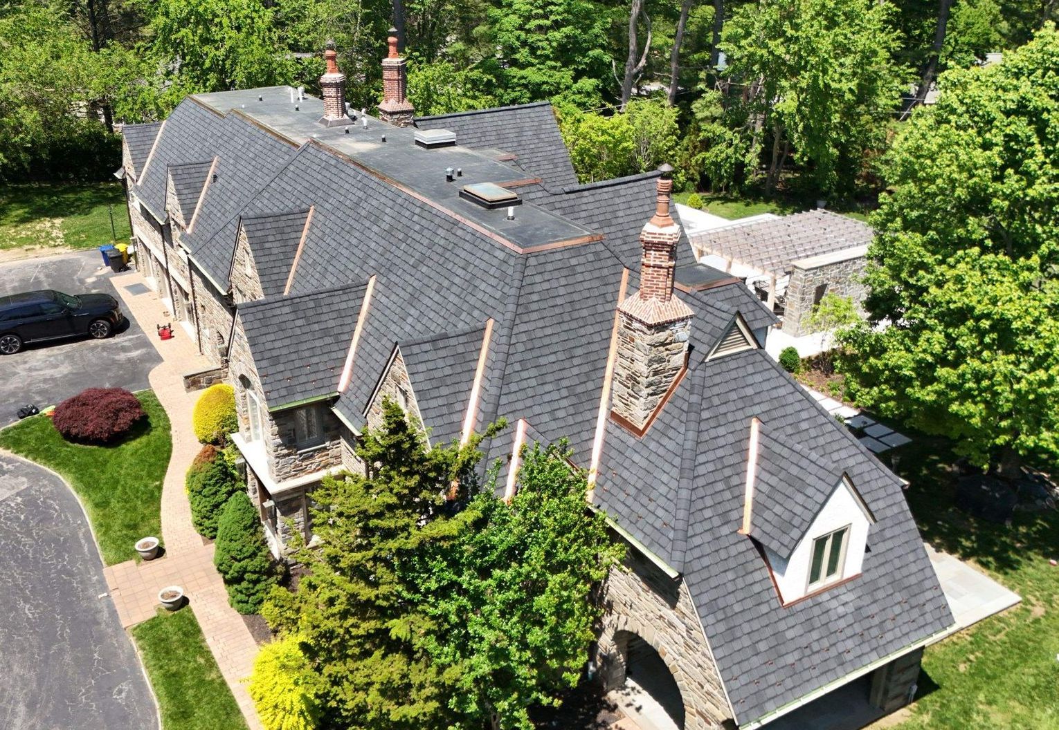 Aerial view of a large gray-roofed house surrounded by trees and landscaping