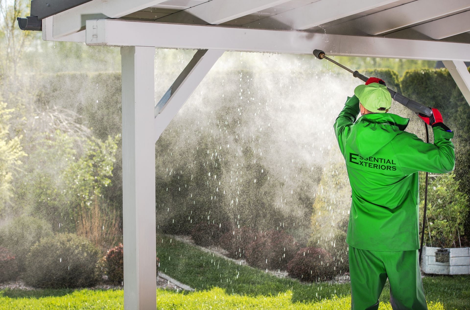 A photo of a man power washing a house.