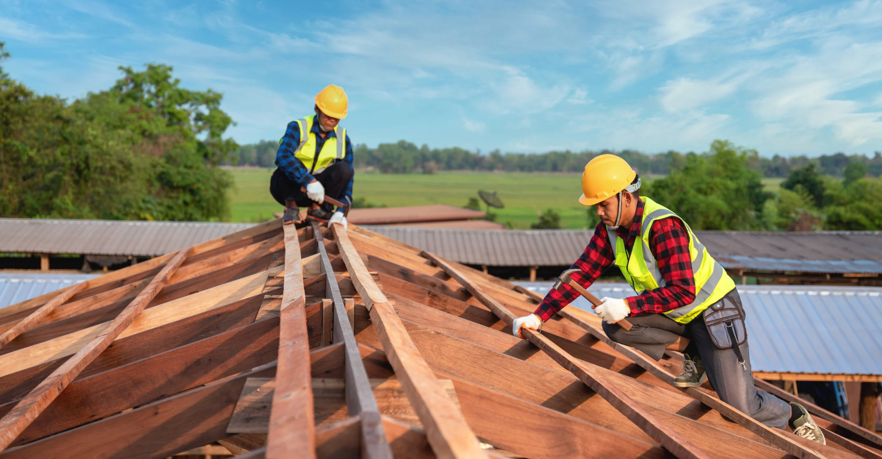 Two construction workers are working on a wooden roof.