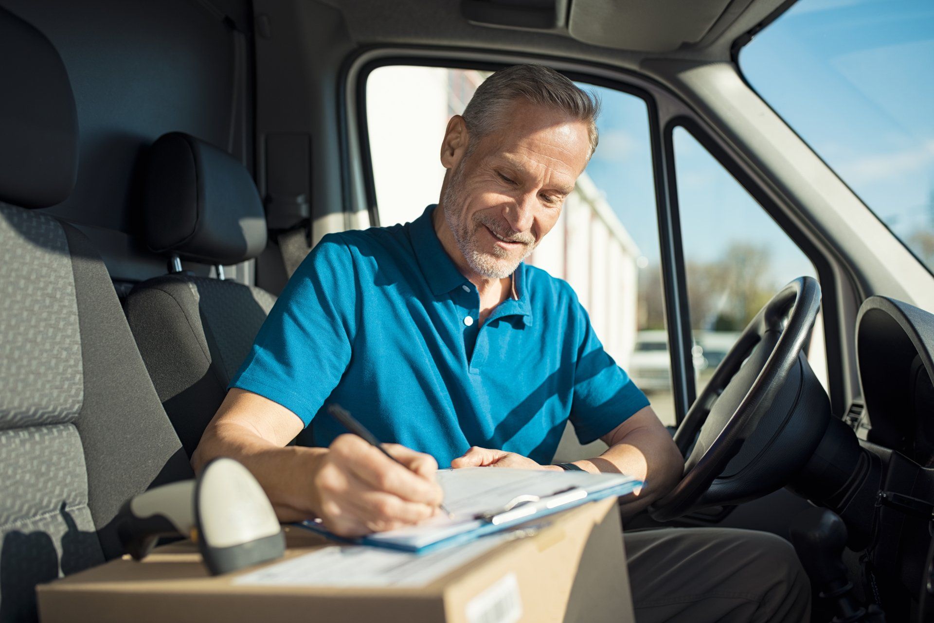 Man in a Car with a Cardboard Box Ready for Delivery — Metairie, LA — Metry Cab Service Man in a Car with a Cardboard Box Ready for Delivery — Metairie, LA — Metry Cab Service