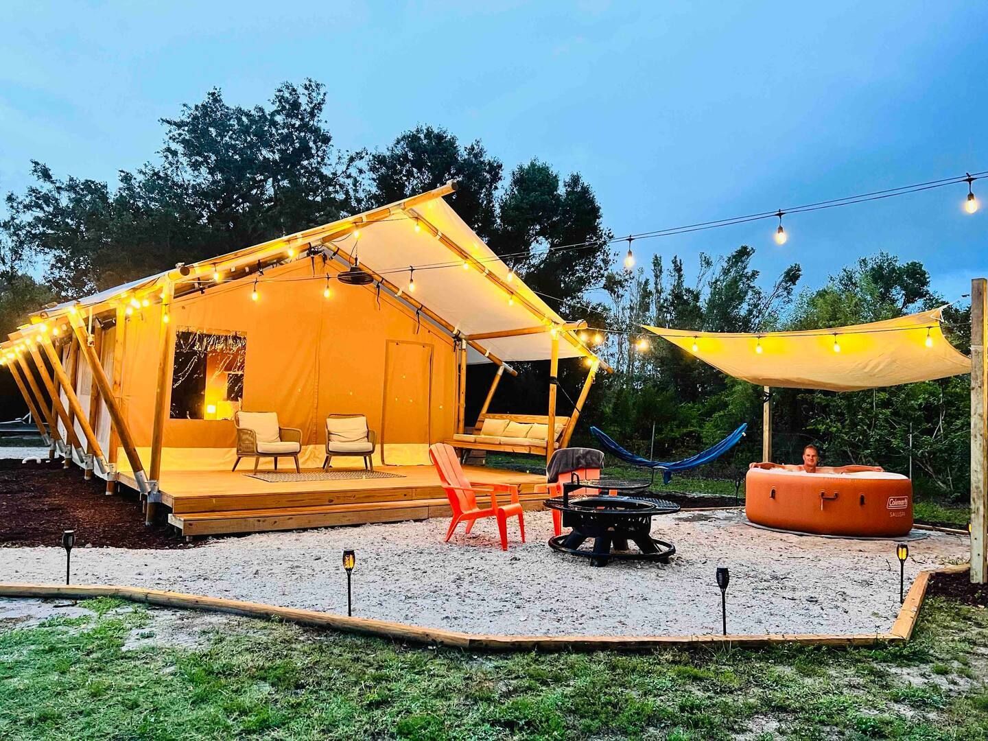 A large tent with a fire pit and chairs in front of it.