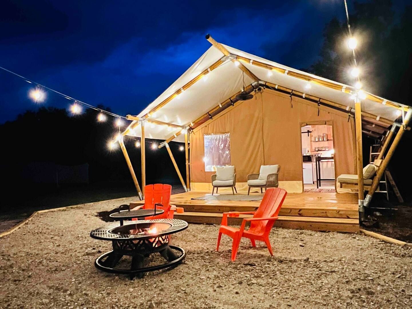 A tent with a fire pit in front of it at night.