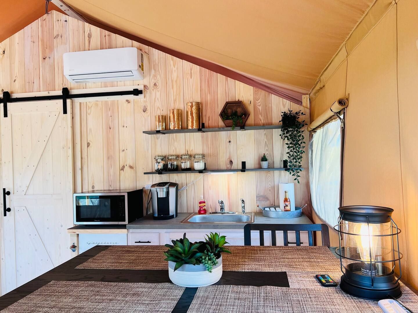 A kitchen with a table , sink , microwave and a lantern.