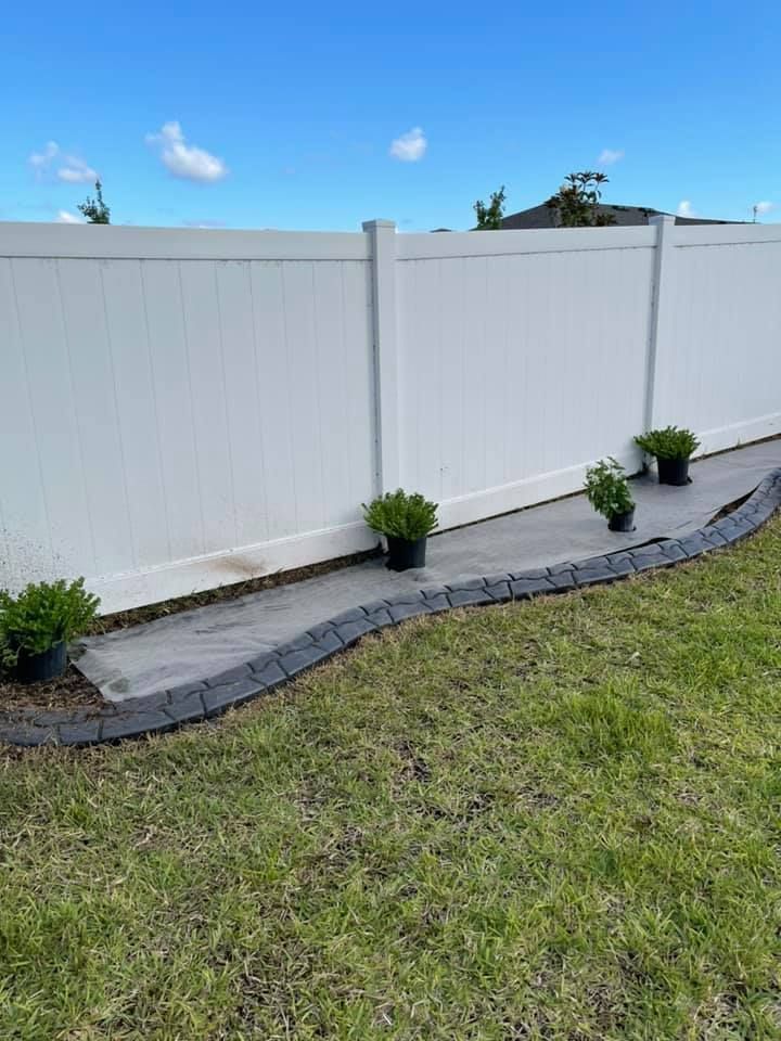 A white fence with potted plants in front of it.