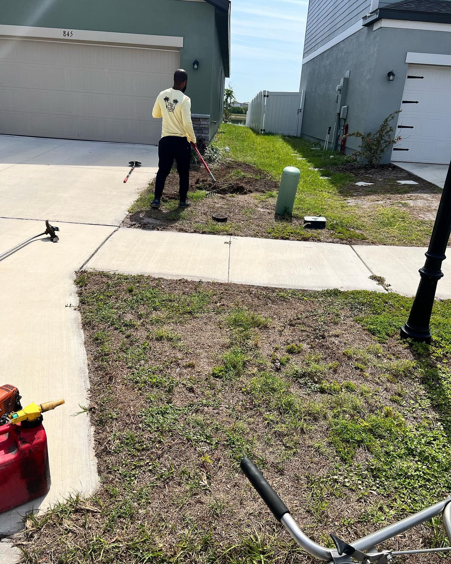 A man is standing in front of a house cutting grass with a lawn mower.