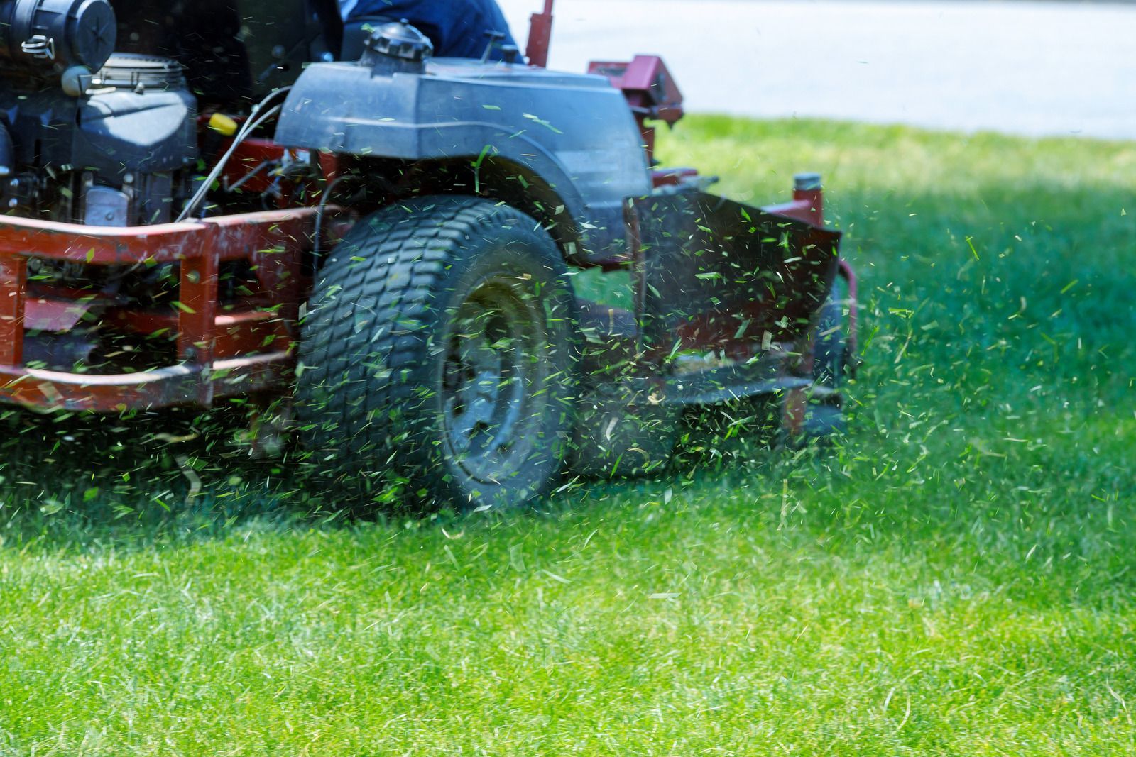 A man is riding a lawn mower on a lush green lawn.