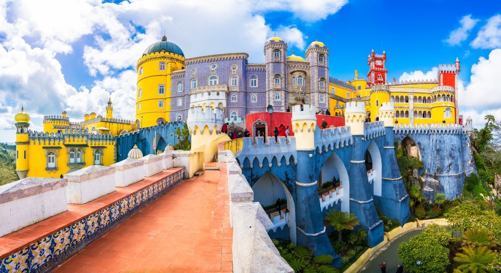 Um castelo situado no topo de uma colina com uma ponte na frente.