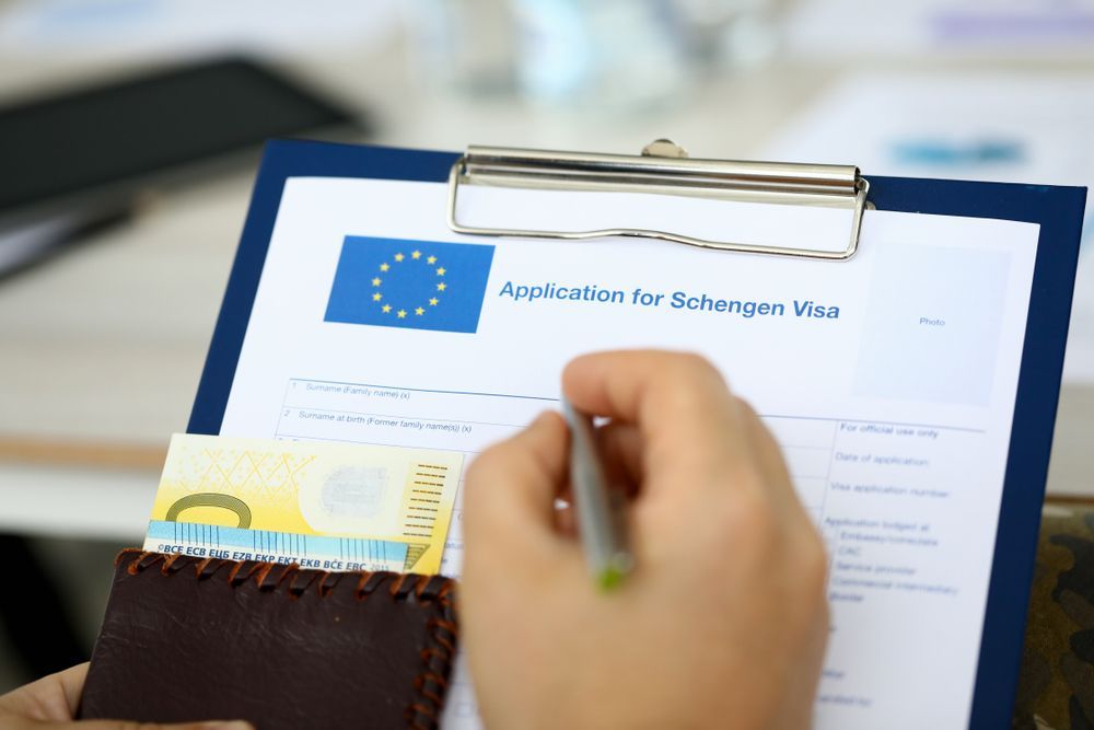 Uma pessoa está escrevendo em uma prancheta com uma nota de euro na carteira