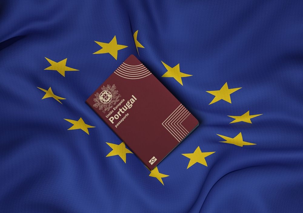 Um passaporte de portugal está em cima de uma bandeira europeia agitando