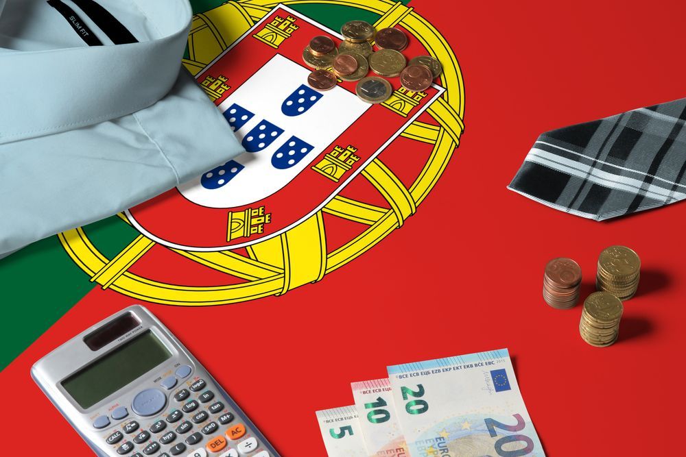 Uma calculadora está sobre uma mesa em frente a uma bandeira portuguesa