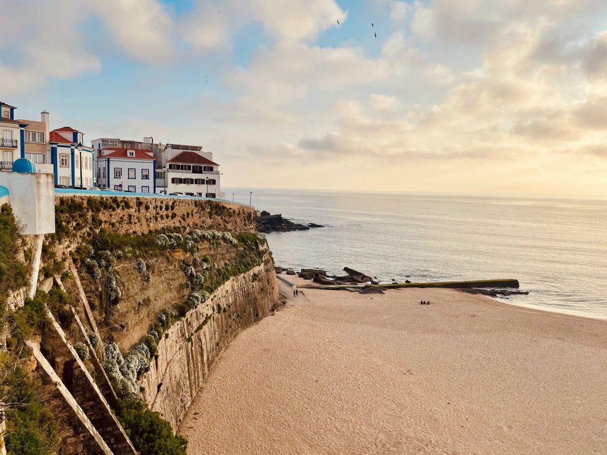 Um penhasco com vista para uma praia com edifícios ao fundo.