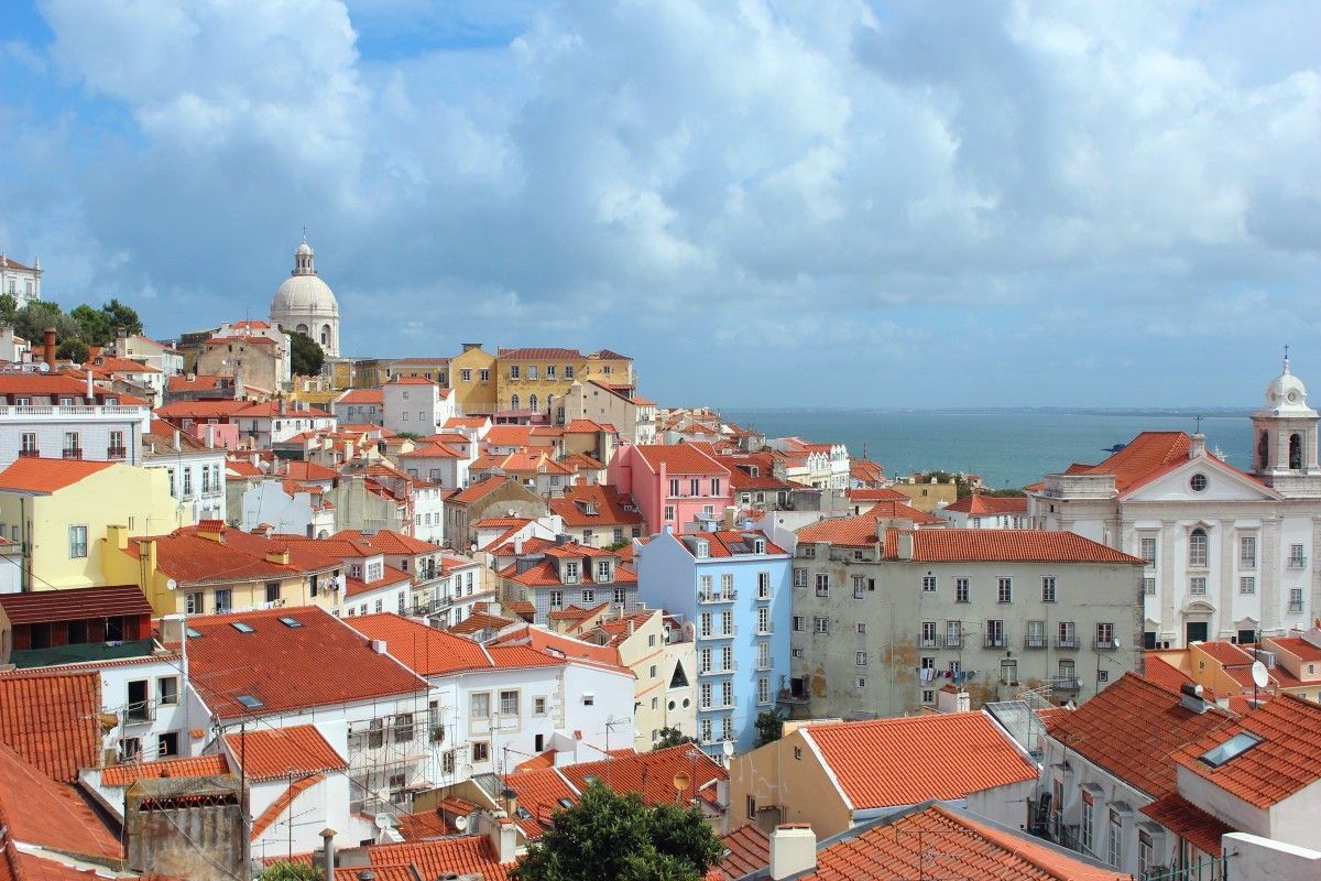 Uma vista aérea de uma cidade com telhados vermelhos e o oceano ao fundo
