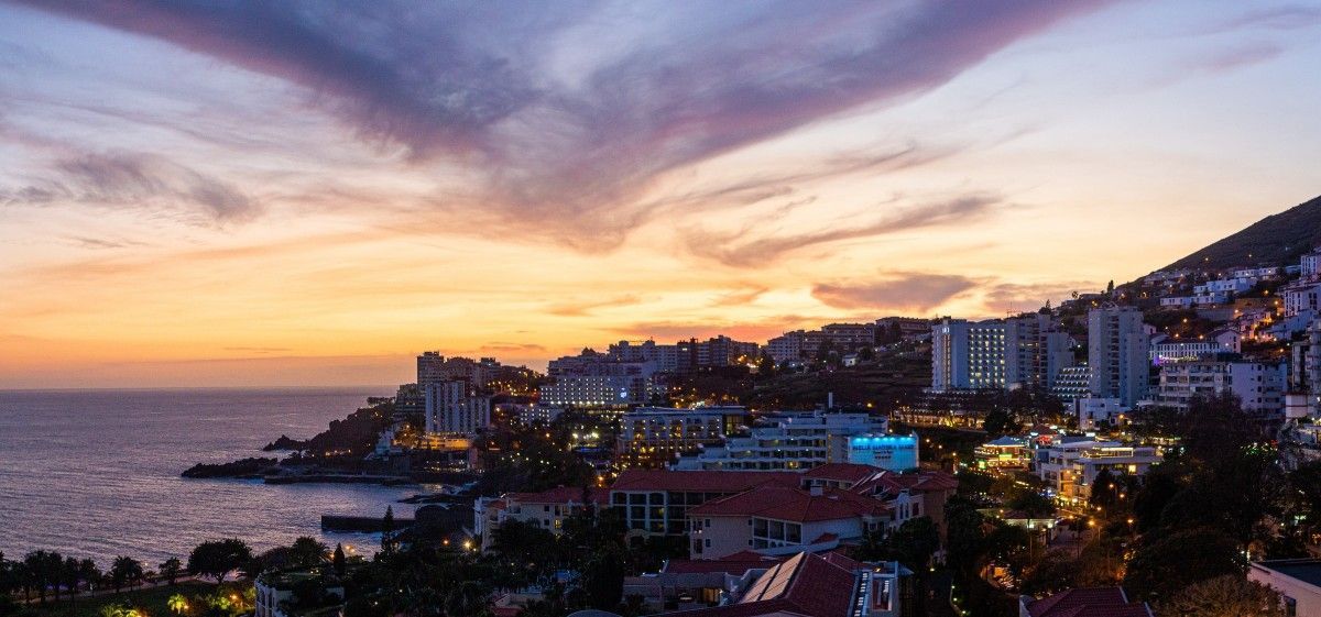 Uma vista aérea de uma cidade perto do oceano ao pôr do sol.
