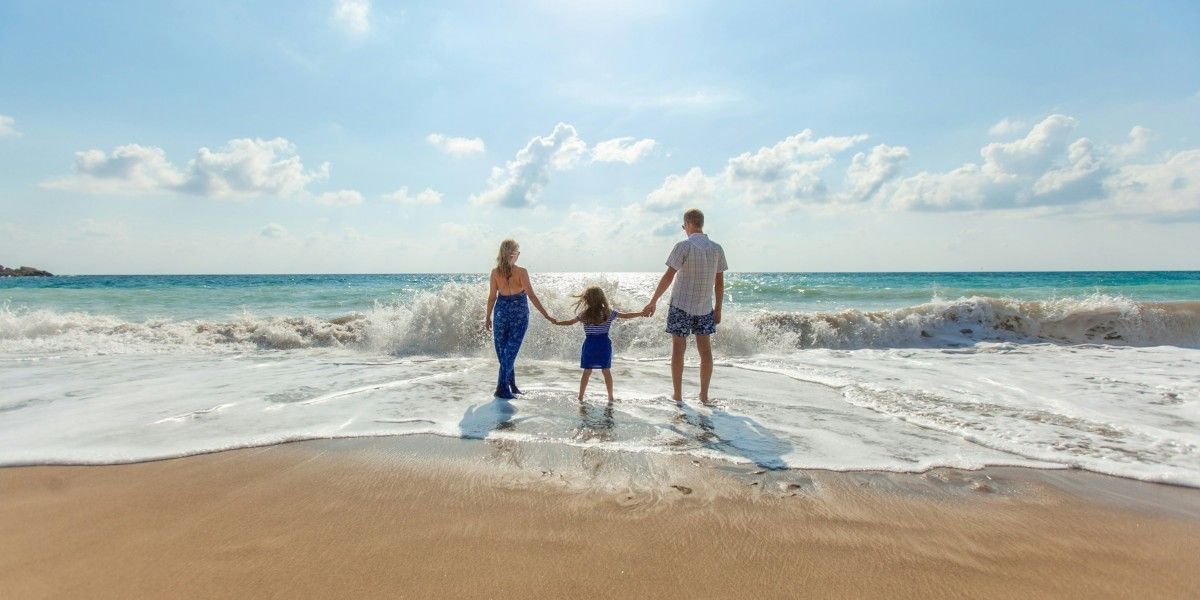 Uma família está andando na praia de mãos dadas.