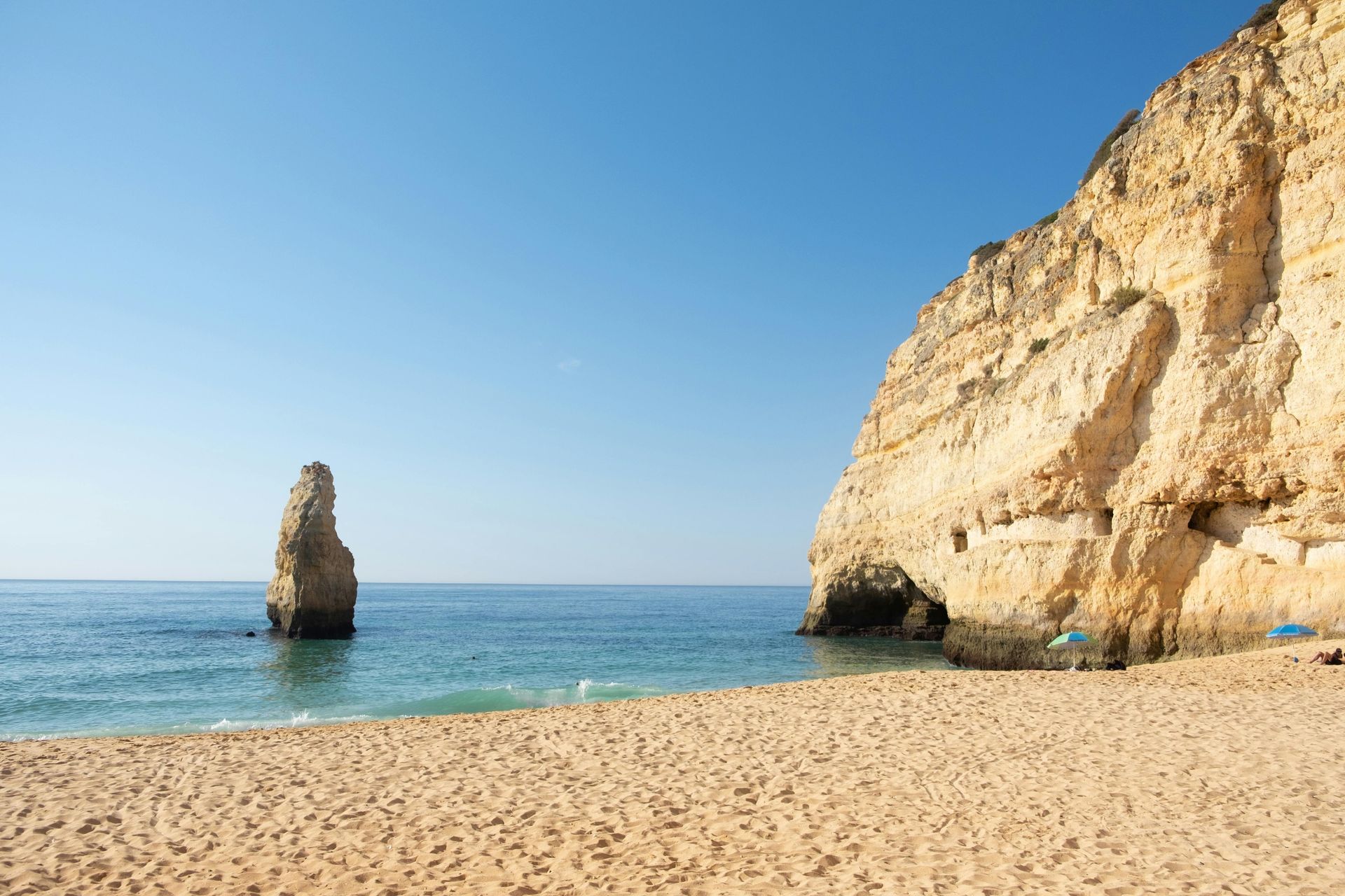 Há uma grande rocha no meio do oceano na praia.