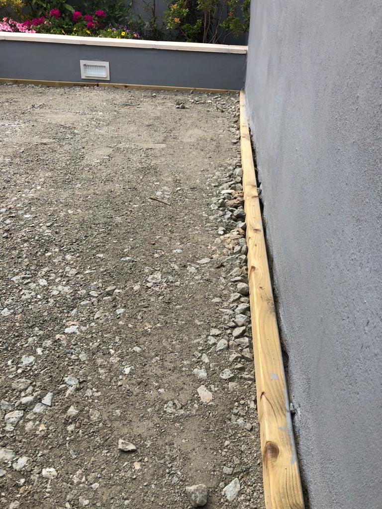 A wooden plank is sitting on the ground next to a wall.