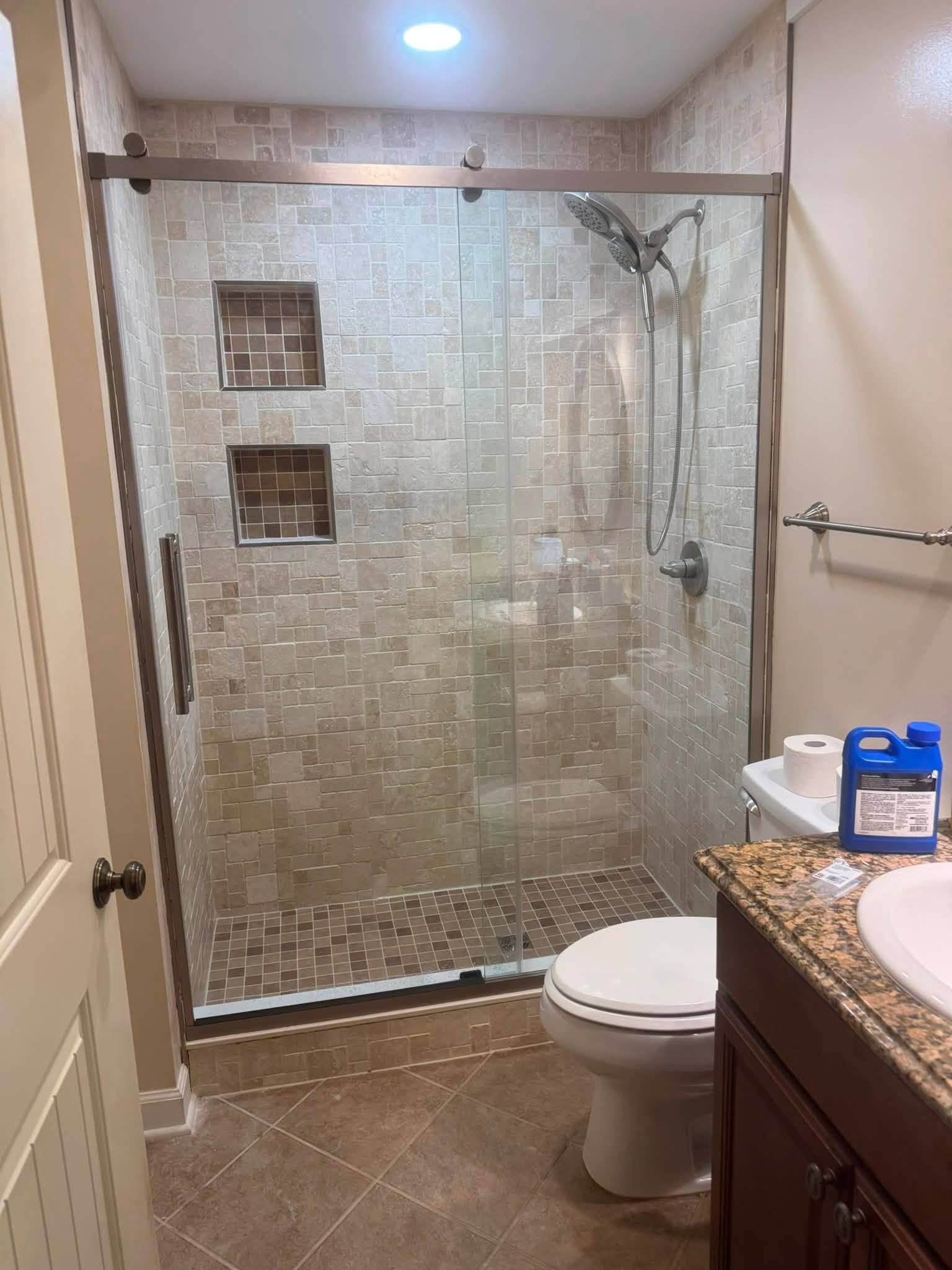 Bathroom with glass-enclosed shower, toilet, and vanity with granite countertop