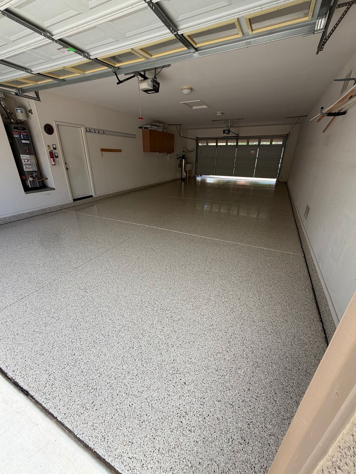 Empty garage with speckled floor, white walls, and an open garage door.