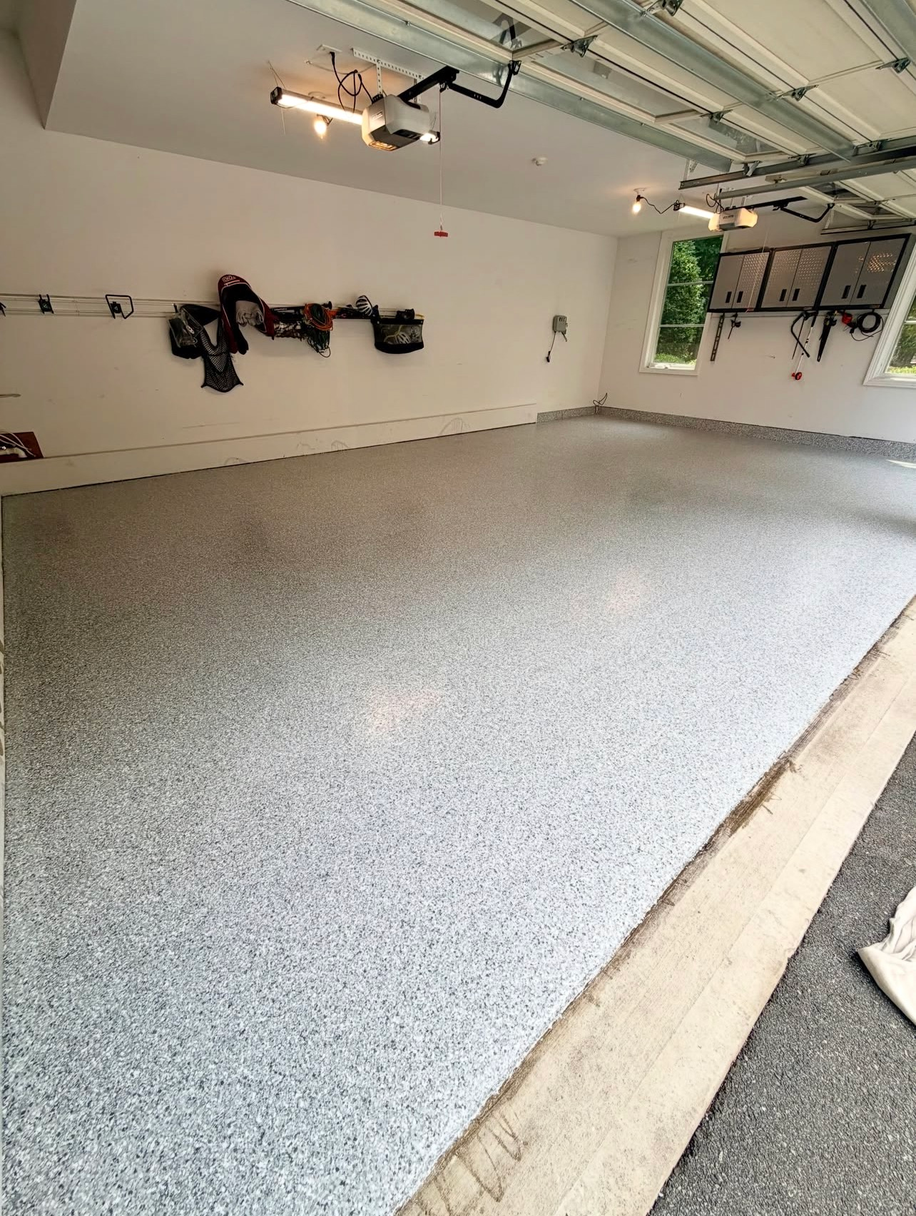 Empty garage with a speckled epoxy floor and wall-mounted bicycles.