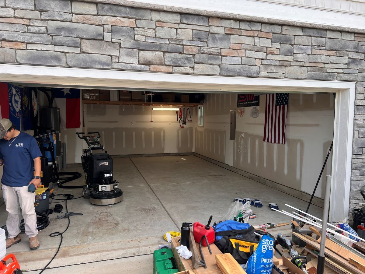 Garage interior being cleaned, with a floor scrubber, tools, and flags on the back wall.
