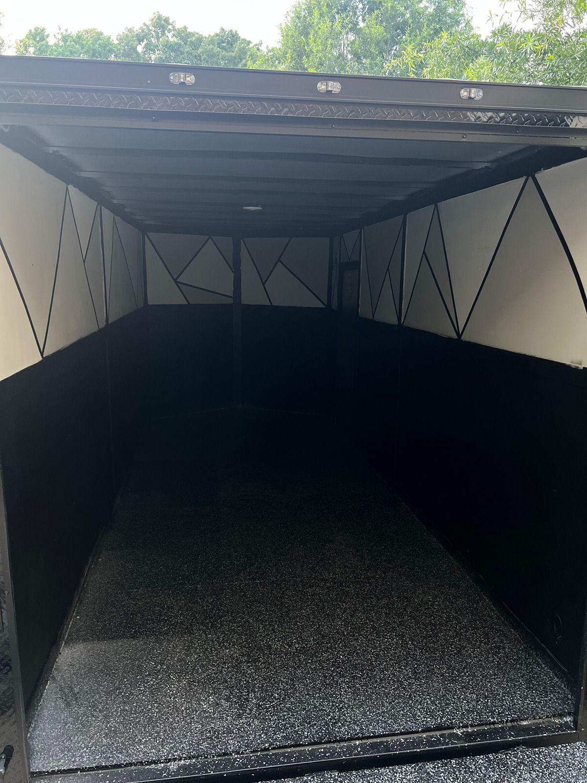 Open cargo trailer interior with black walls and textured floor mat