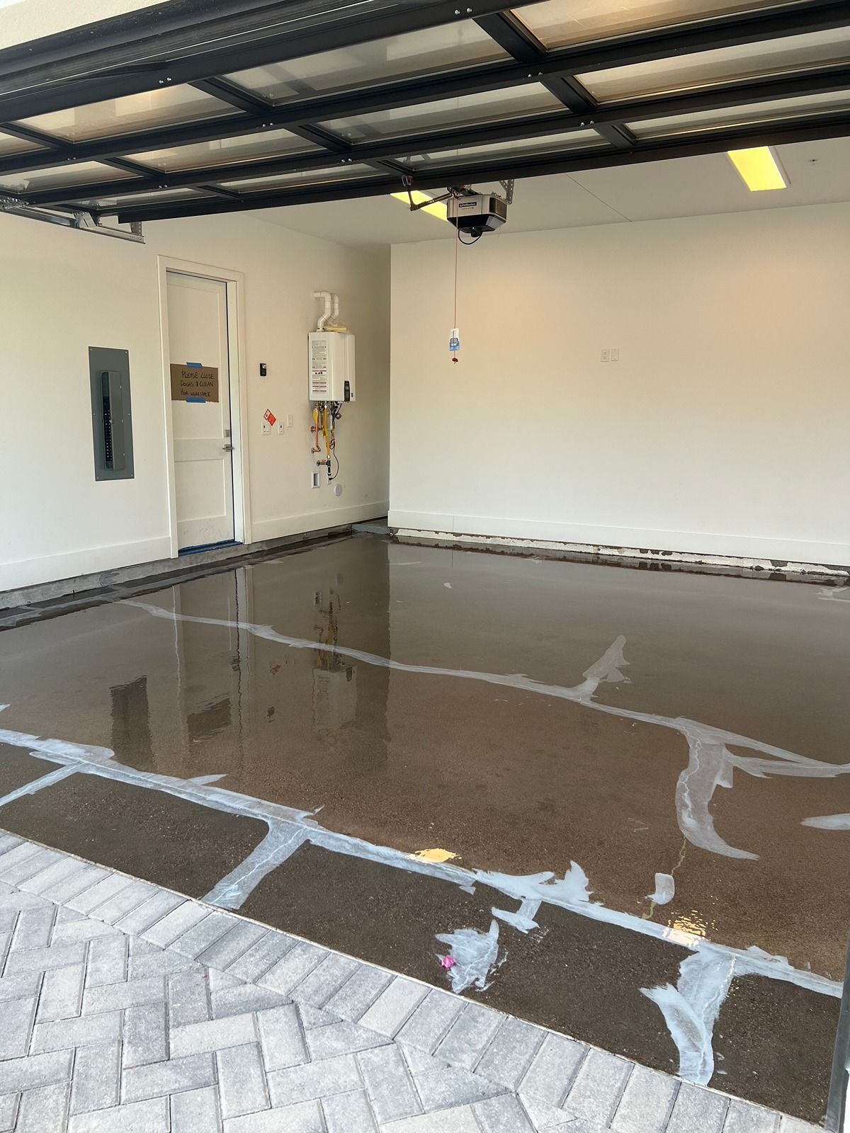 Garage interior with wet floor, white walls, and open garage door.