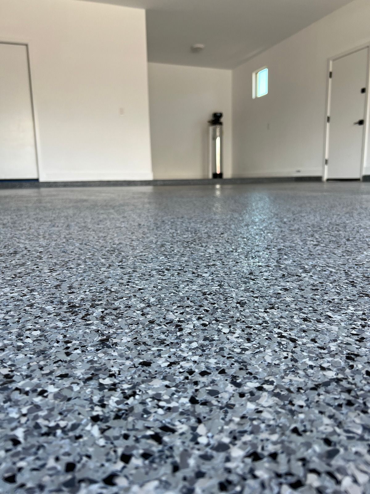 Empty garage with speckled epoxy floor and white walls, viewed from low angle