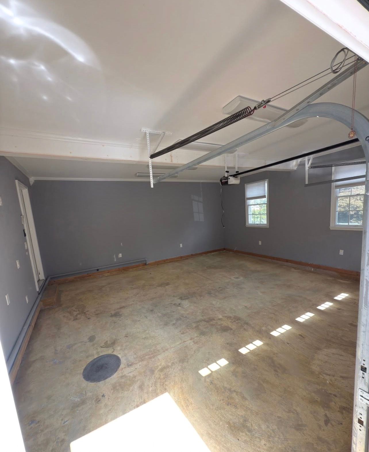 Empty gray garage interior with bare plywood floor and open ceiling storage rack