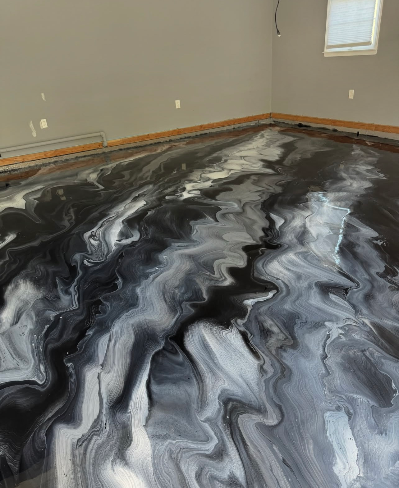 Black-and-gray marbled epoxy floor in an empty room with beige walls and a small window