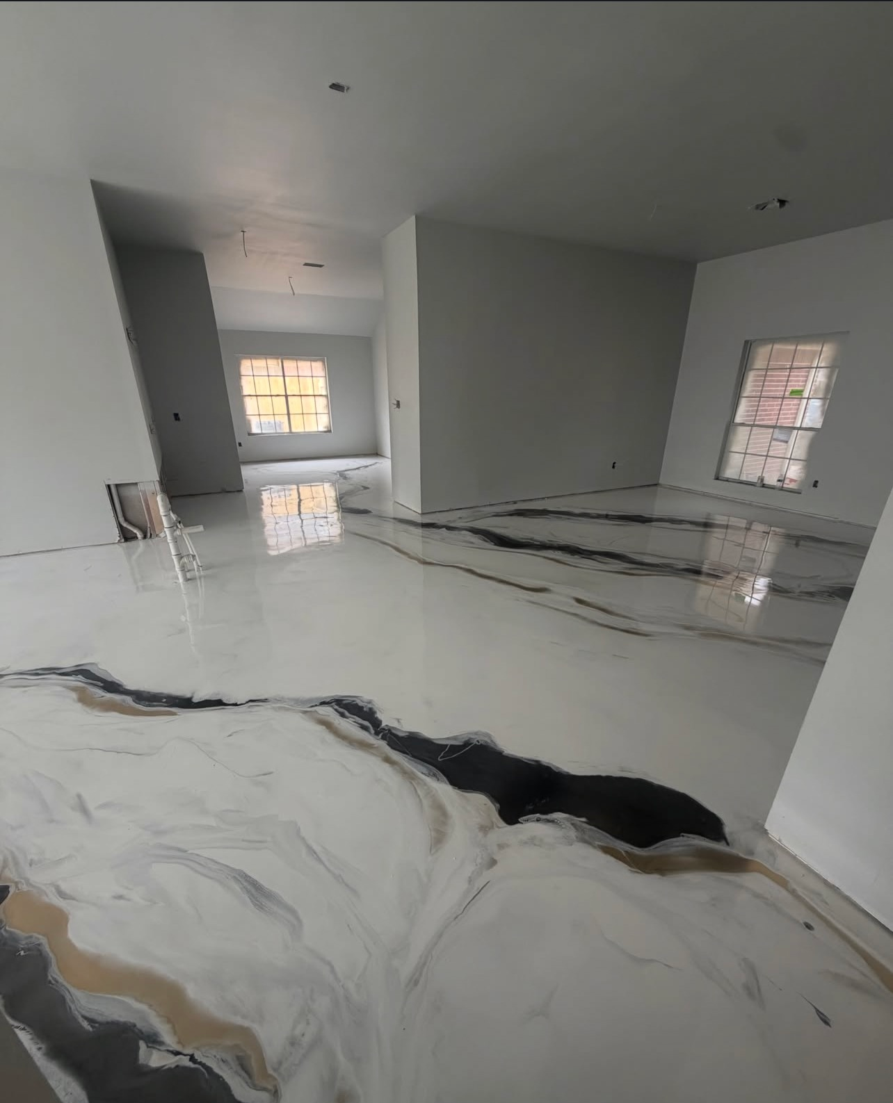 Bright empty room with glossy white marble floor and black veining, gray walls, and windows.