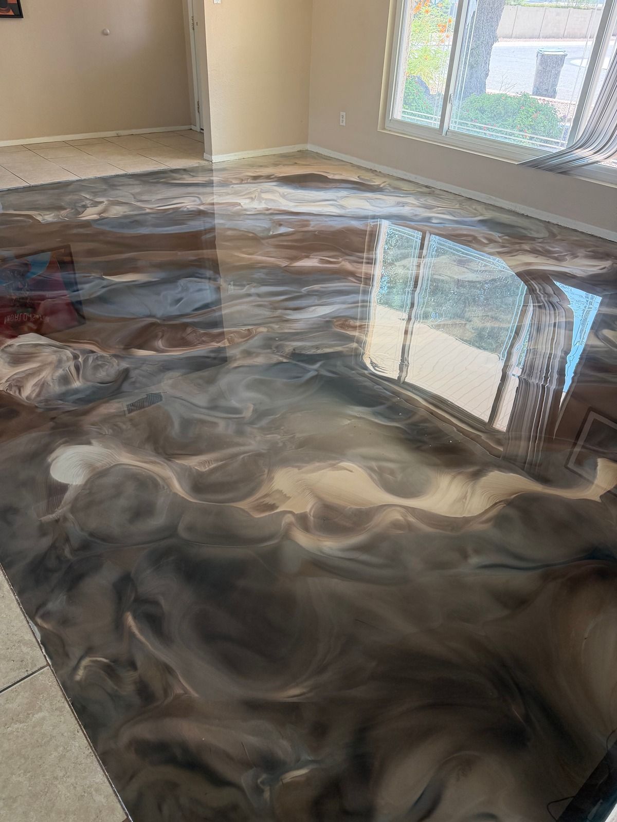 Swirling black and white epoxy floor in a sunlit room with windows and beige walls