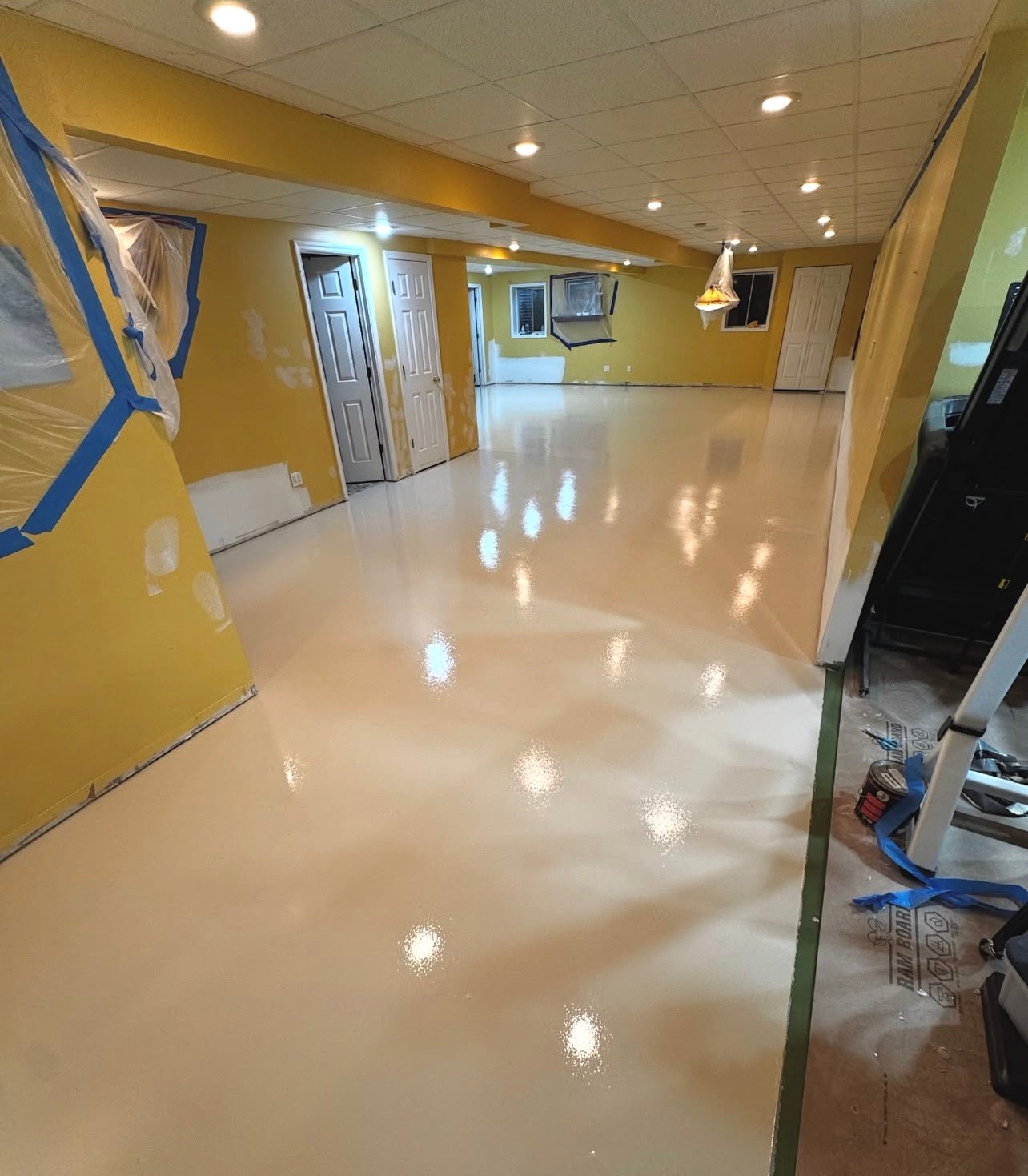 Empty freshly painted room with glossy beige floor, yellow walls, and recessed ceiling lights