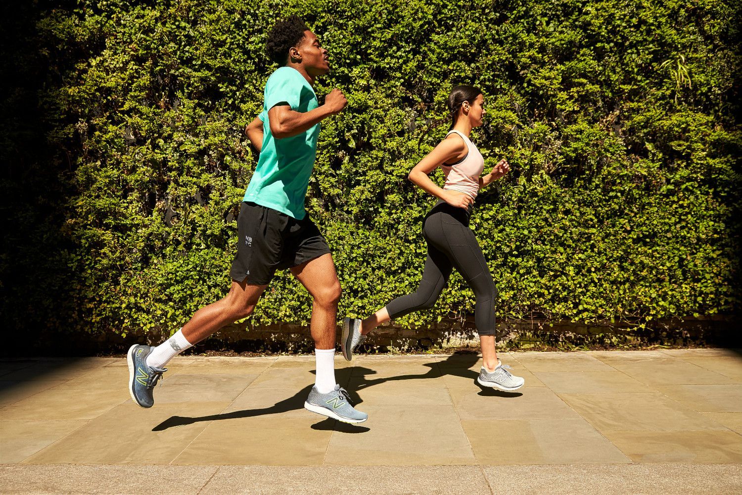 A man and a woman are running on a sidewalk.