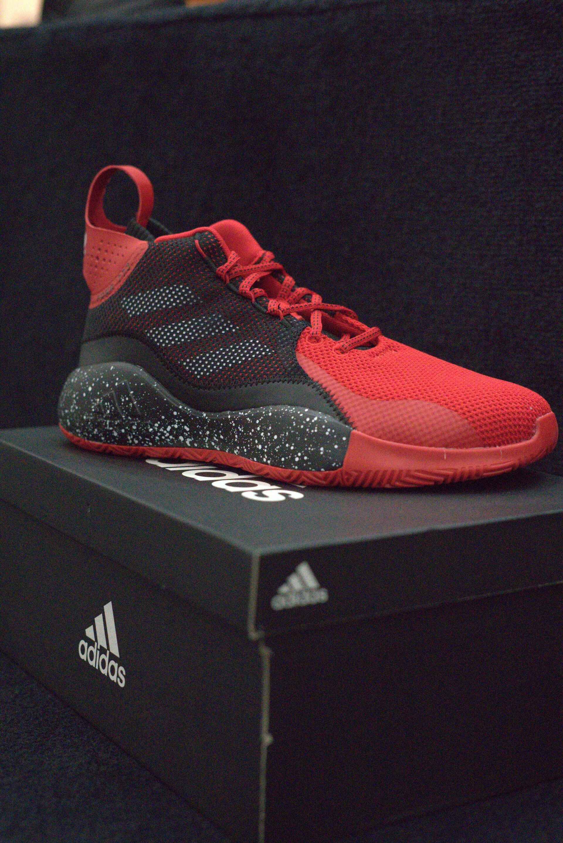 A pair of red and black adidas shoes sitting on top of a black box.