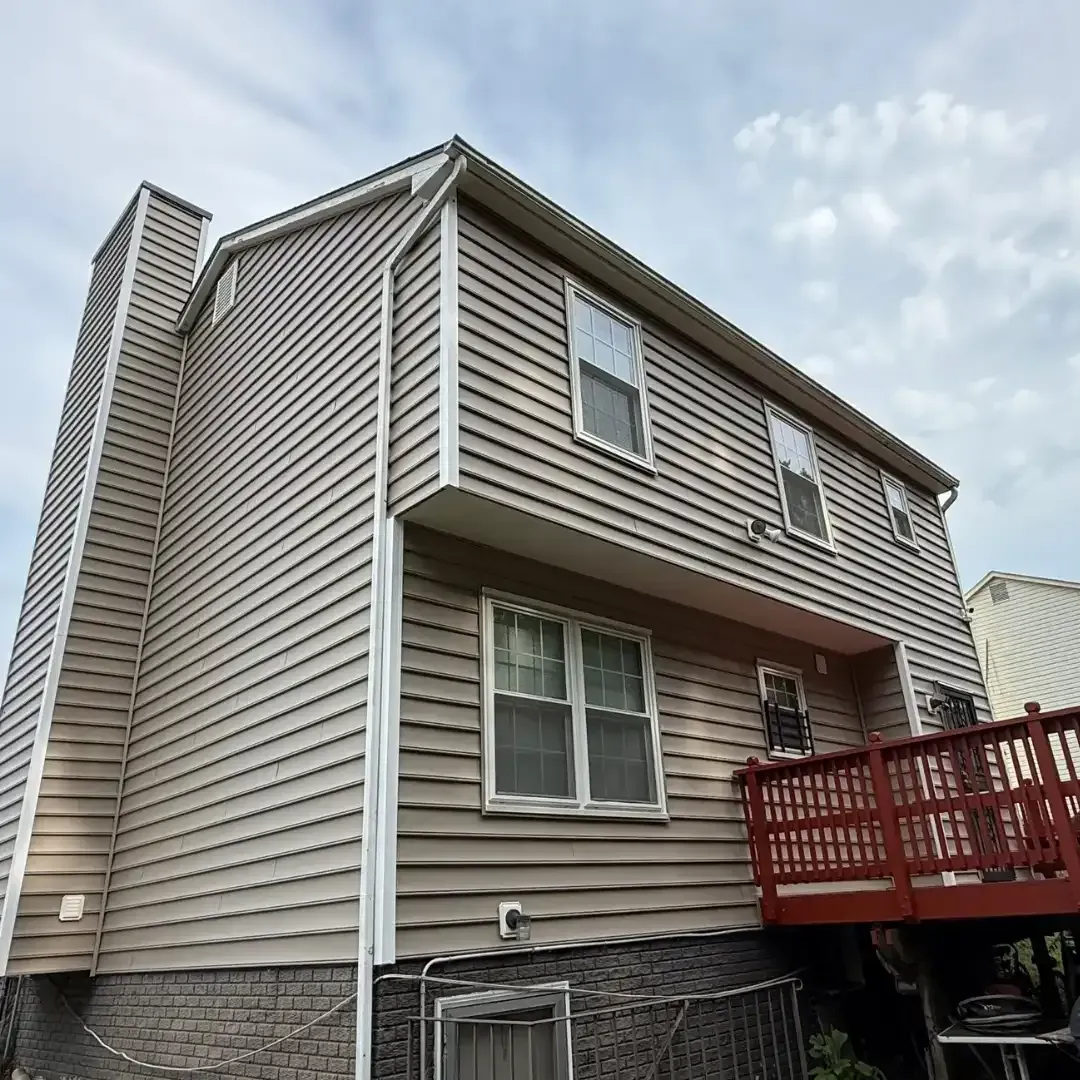 Two-story beige house with white trim and a red wooden deck