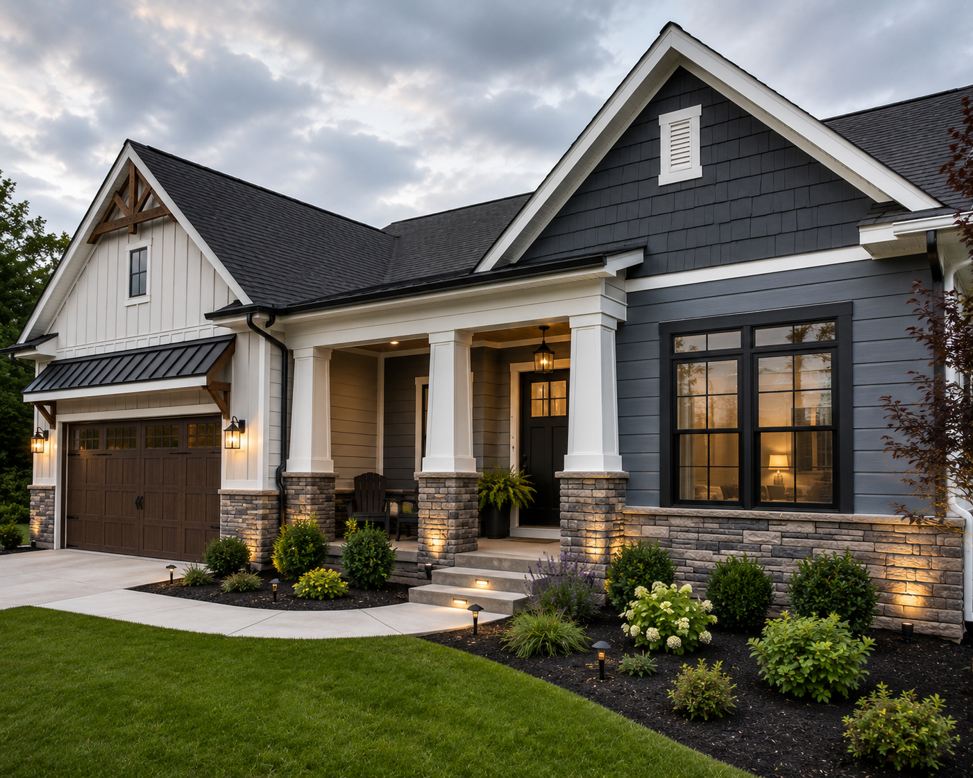 Modern gray suburban house with stone accents, lit porch, garage, and manicured front lawn at dusk