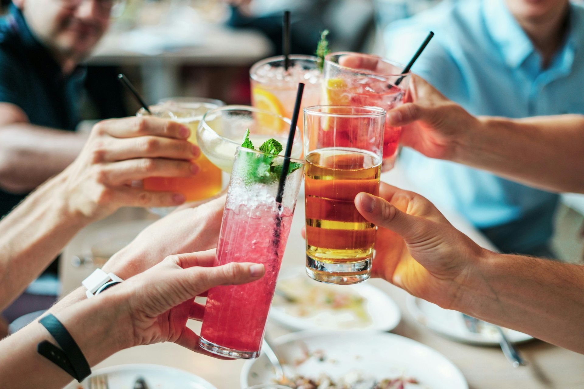 Handen heffen kleurrijke drankjes op tijdens een restauranttoast.