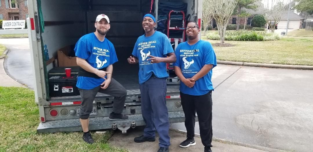 Three people in blue shirts pose beside a truck on a roadside.