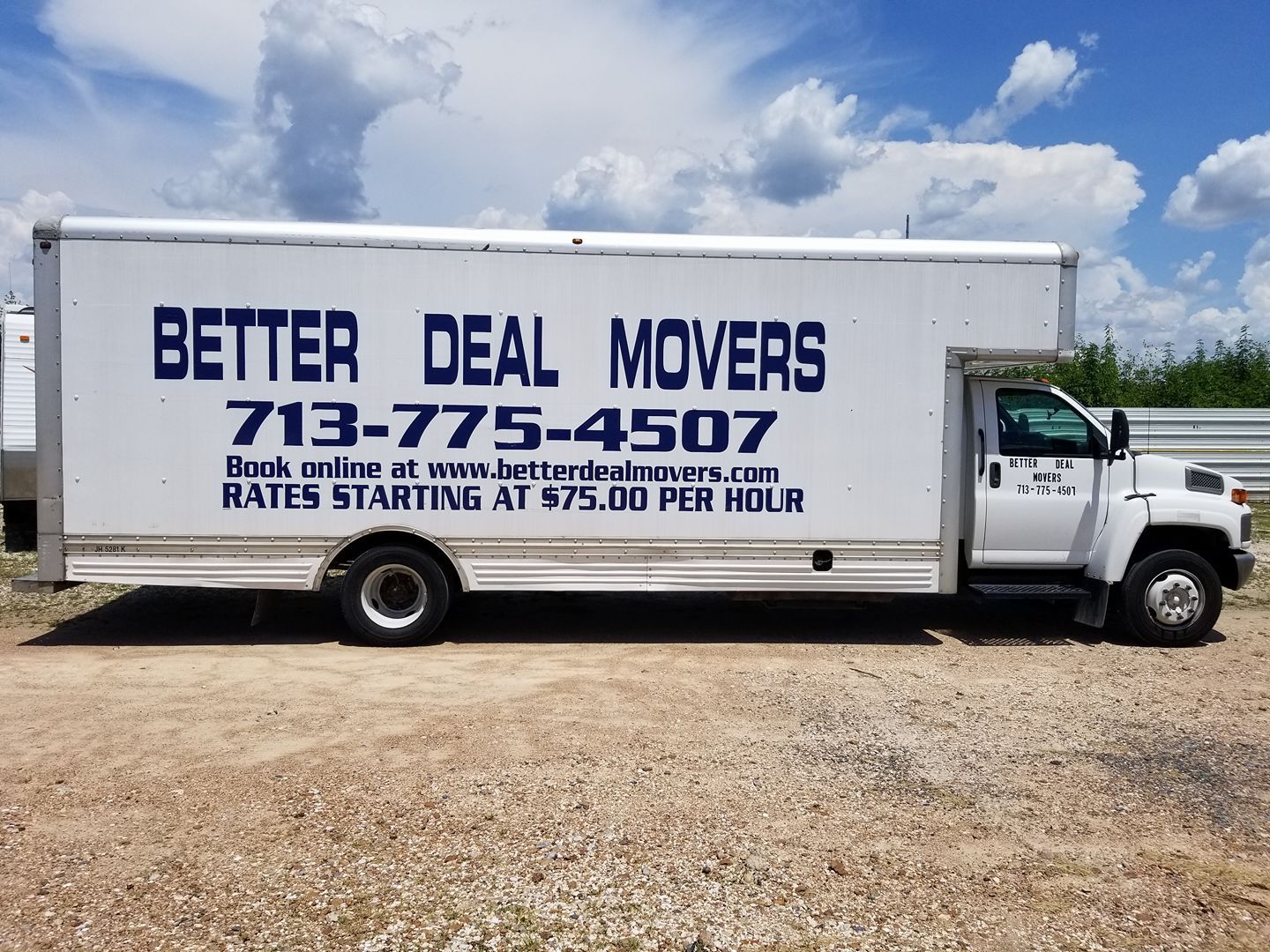 White Better Deal Movers truck with company name and phone number parked on a gravel lot under a blue sky.