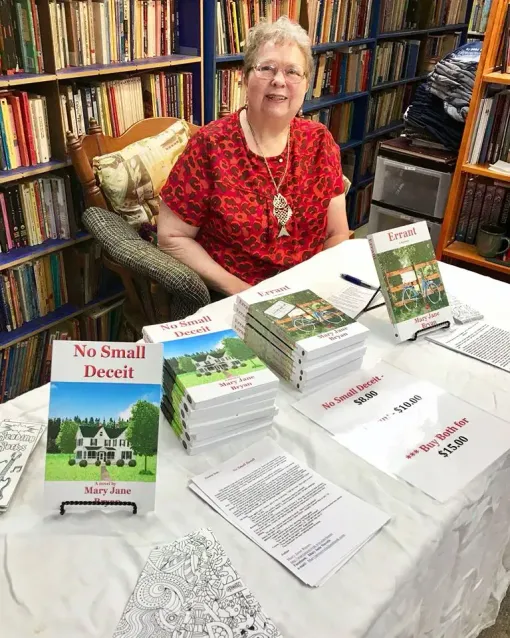 Woman at a book table with stacks of books titled 
