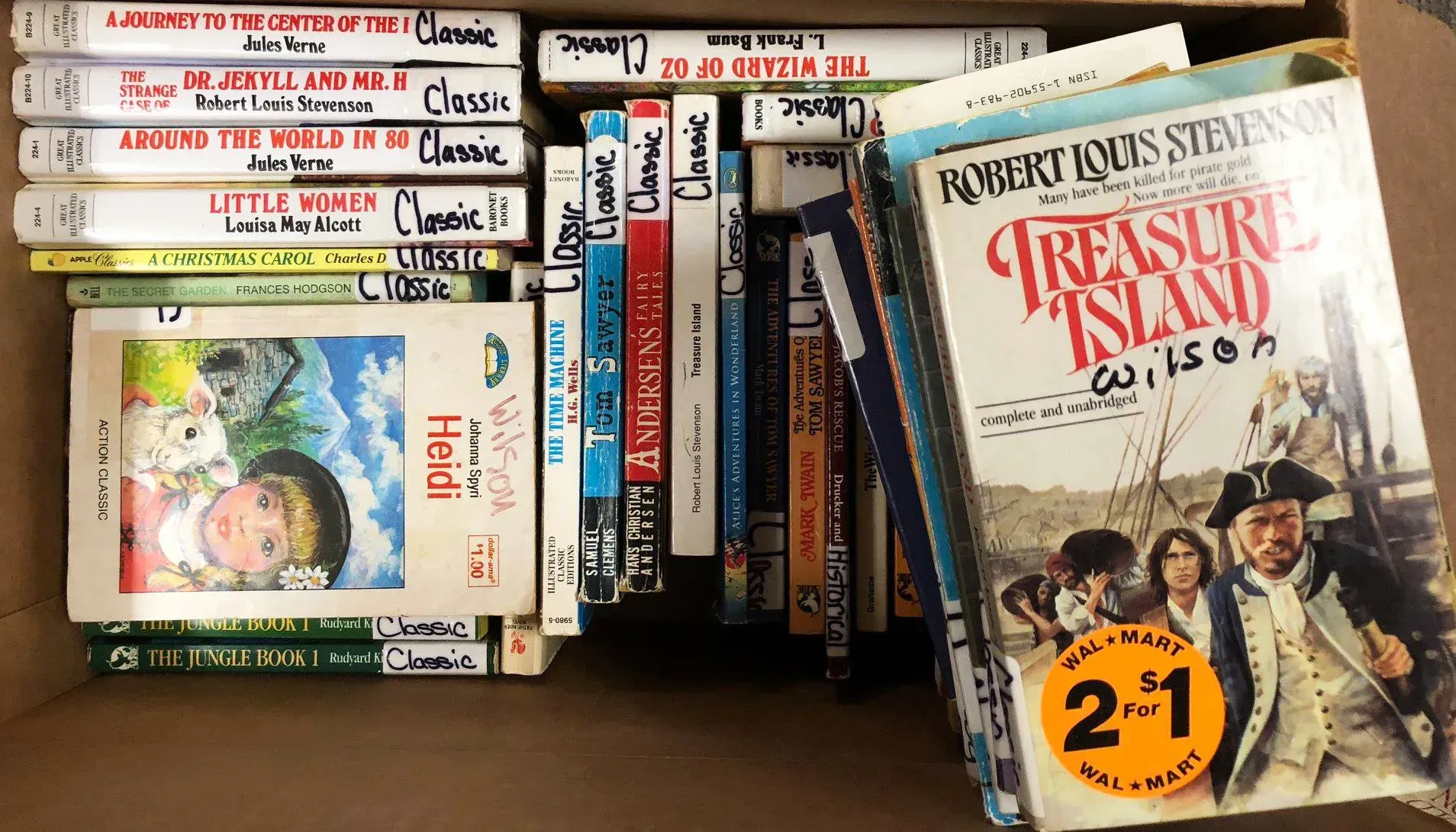Stacked and scattered VHS tapes on a shelf, including Treasure Island, with colorful children’s covers