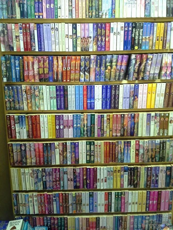 Bookshelves filled with colorful books, mostly light colors.